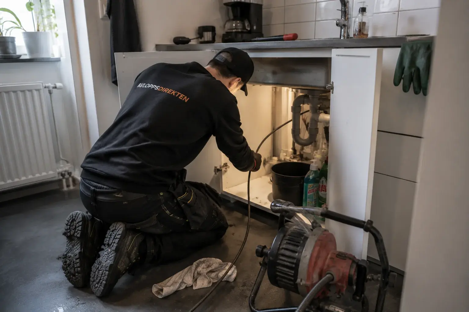 Avloppsarbete under en diskbänk i en bostad